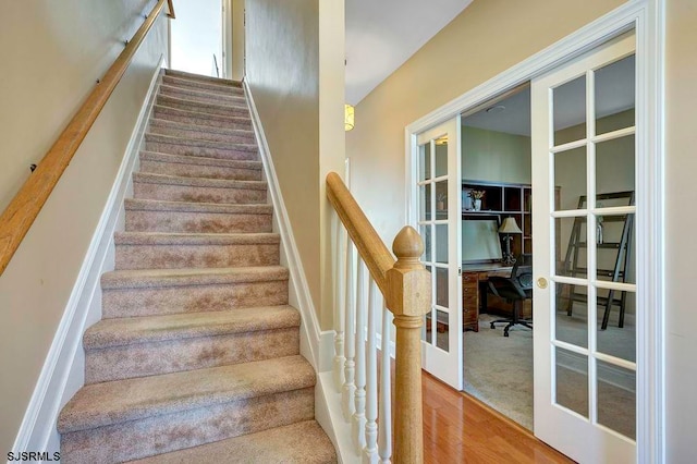 stairs featuring french doors and hardwood / wood-style floors