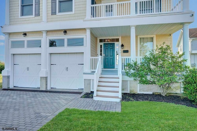 entrance to property featuring a garage, a lawn, and covered porch