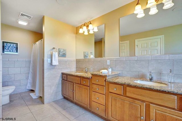 bathroom featuring tile walls, vanity, toilet, a chandelier, and tile patterned floors