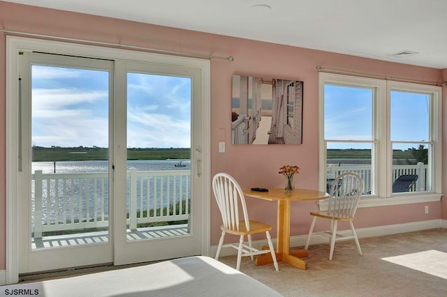 carpeted dining room featuring a water view and a healthy amount of sunlight