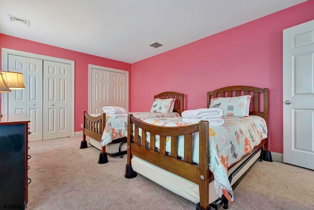 bedroom with two closets and light carpet