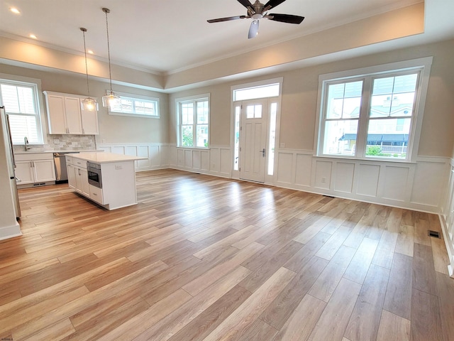 kitchen with pendant lighting, ceiling fan, a kitchen island, white cabinetry, and stainless steel appliances