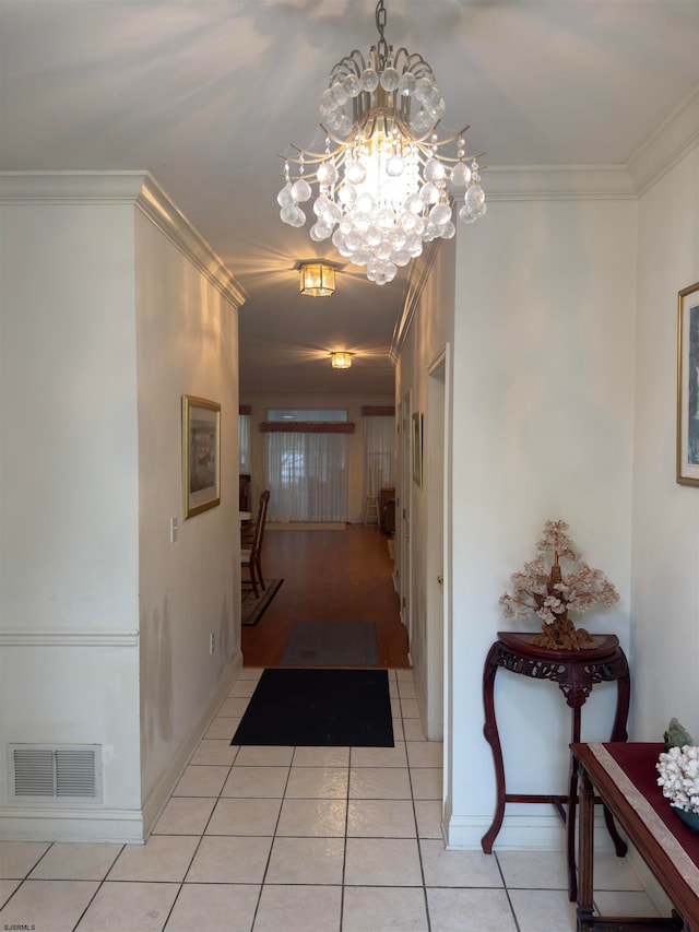 hallway with light tile patterned floors, crown molding, and an inviting chandelier