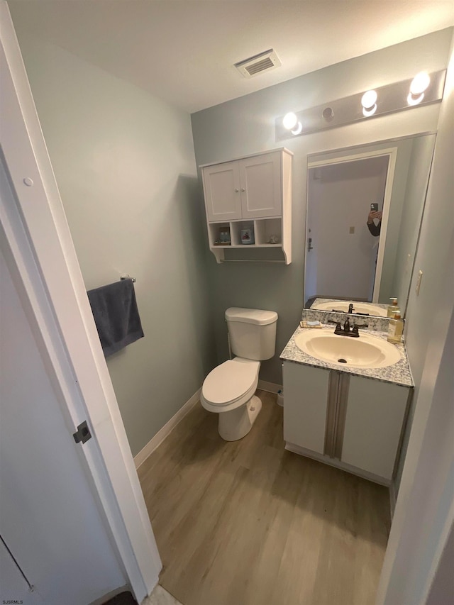 bathroom with vanity, toilet, and hardwood / wood-style flooring