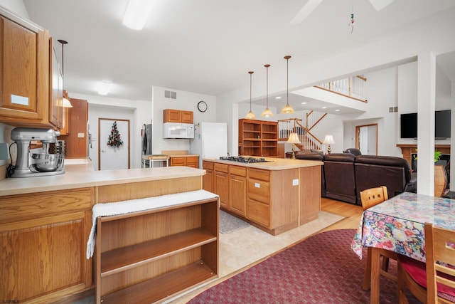 kitchen featuring pendant lighting, light hardwood / wood-style floors, a center island, stainless steel gas cooktop, and ceiling fan