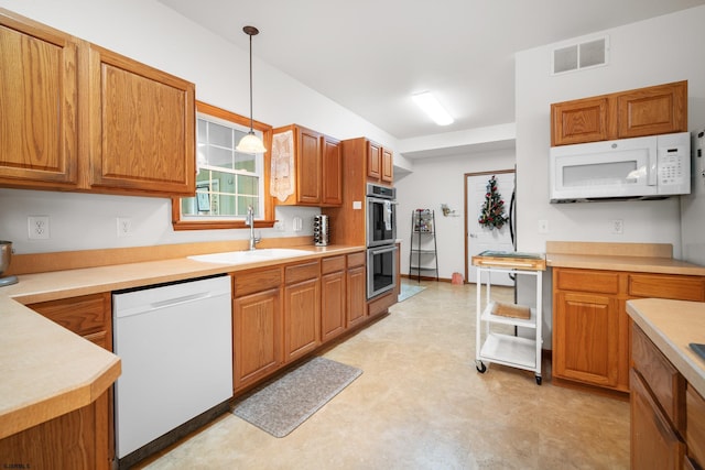 kitchen with pendant lighting, white appliances, and sink