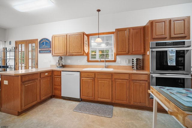 kitchen featuring hanging light fixtures, kitchen peninsula, dishwasher, double oven, and sink