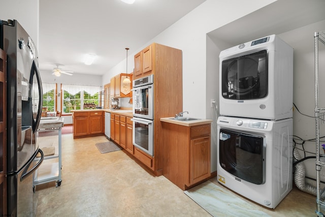 kitchen featuring pendant lighting, stainless steel appliances, stacked washer / drying machine, ceiling fan, and sink