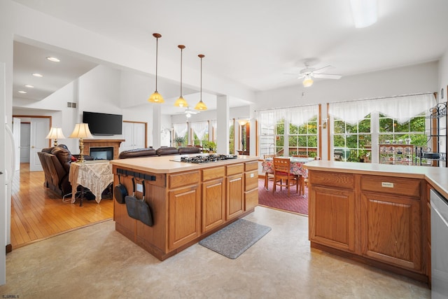 kitchen featuring a center island, stainless steel gas cooktop, hanging light fixtures, light hardwood / wood-style flooring, and ceiling fan