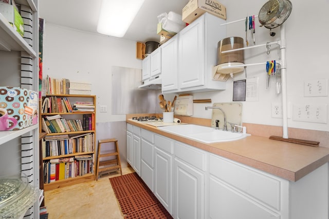 kitchen featuring white gas stovetop, sink, and white cabinetry