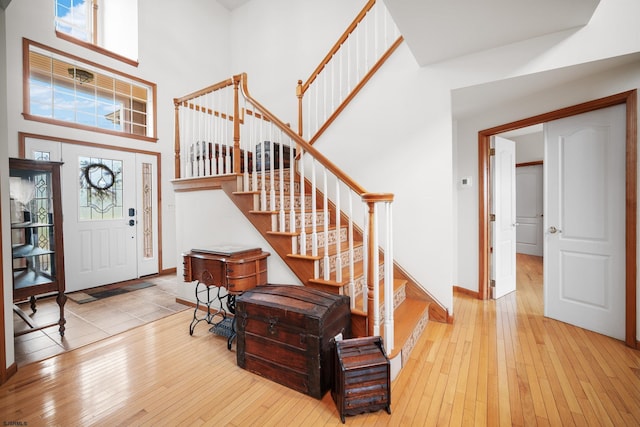 foyer entrance featuring light wood-type flooring and a towering ceiling