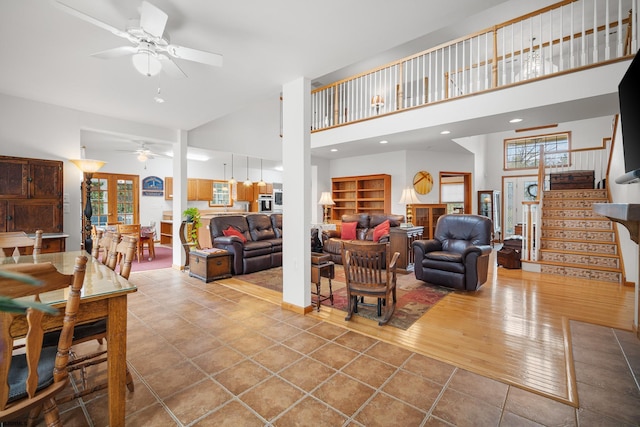 living room with ceiling fan, light wood-type flooring, and a high ceiling