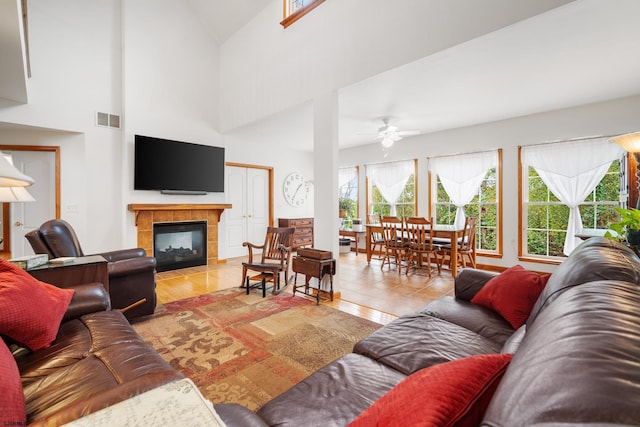 tiled living room with ceiling fan, a fireplace, and high vaulted ceiling