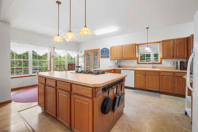 kitchen featuring a kitchen island, stainless steel gas cooktop, dishwasher, decorative light fixtures, and sink