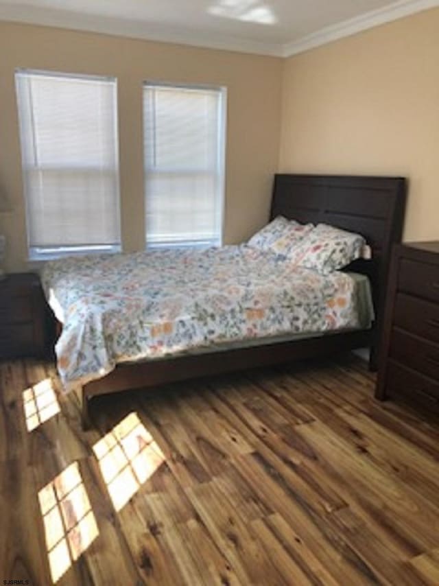 bedroom with multiple windows, ornamental molding, and hardwood / wood-style flooring