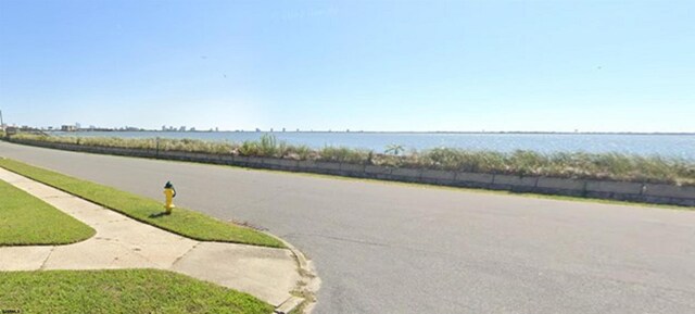 view of street with curbs, a water view, and sidewalks
