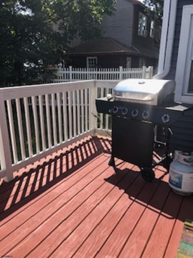 wooden deck featuring fence and a grill
