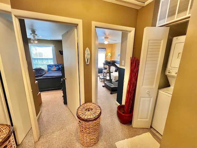 hall featuring stacked washer and clothes dryer and light colored carpet