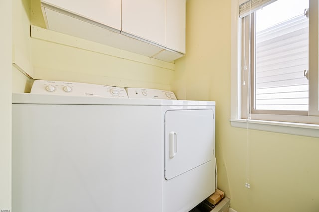 clothes washing area with washing machine and dryer and cabinets