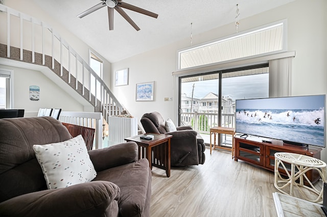 living room with ceiling fan, light hardwood / wood-style flooring, plenty of natural light, and lofted ceiling