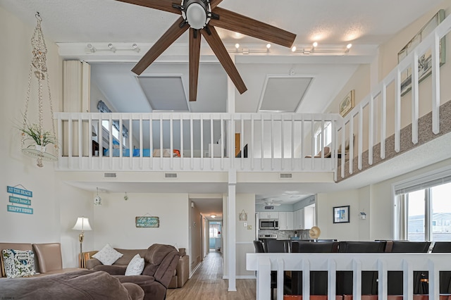 living room featuring lofted ceiling, hardwood / wood-style floors, ceiling fan, and track lighting