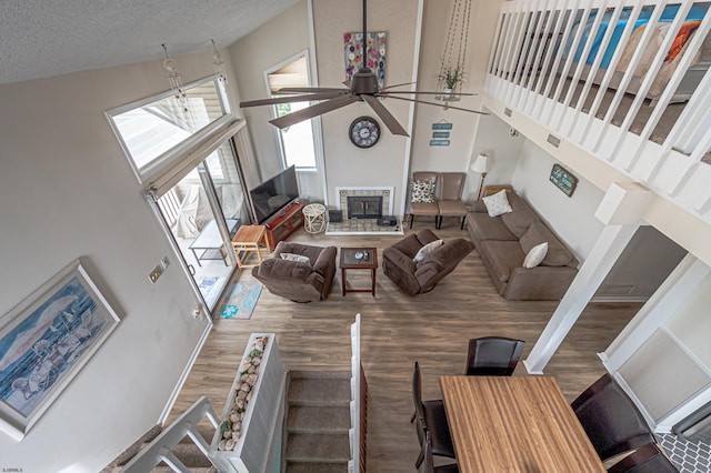 living room with high vaulted ceiling, ceiling fan, hardwood / wood-style floors, and a textured ceiling