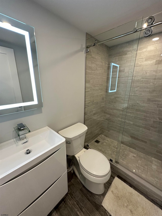 bathroom with wood-type flooring, vanity, walk in shower, and toilet