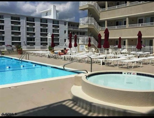 view of pool with a patio and a hot tub