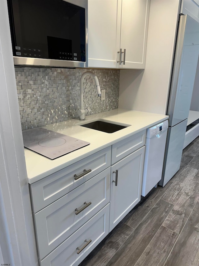 kitchen with dark hardwood / wood-style flooring, white cabinets, sink, and white appliances