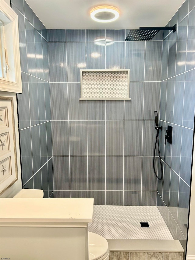 bathroom featuring tiled shower and toilet