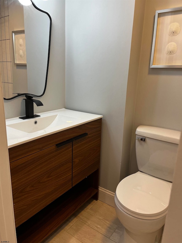 bathroom with wood-type flooring, vanity, and toilet