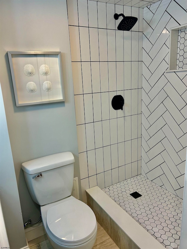 bathroom with a tile shower and toilet