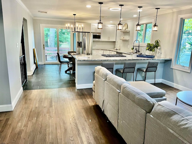 kitchen with decorative light fixtures, plenty of natural light, stainless steel appliances, and white cabinets