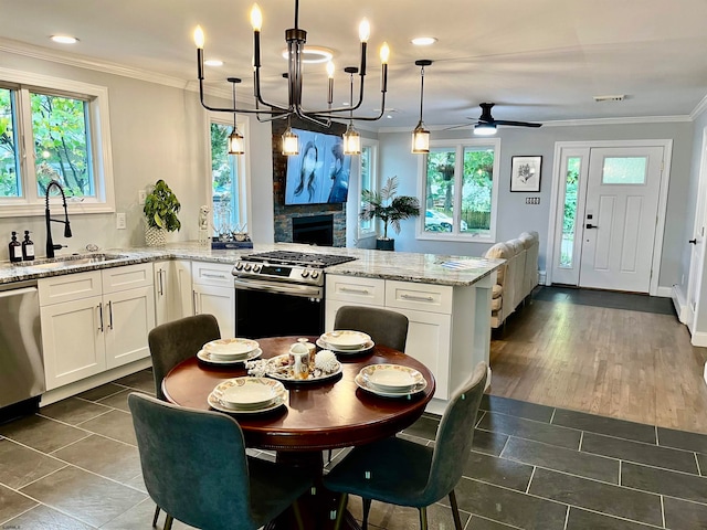 kitchen with white cabinets, decorative light fixtures, appliances with stainless steel finishes, dark hardwood / wood-style floors, and ceiling fan with notable chandelier