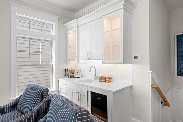 kitchen featuring white cabinets, sink, beverage cooler, backsplash, and crown molding