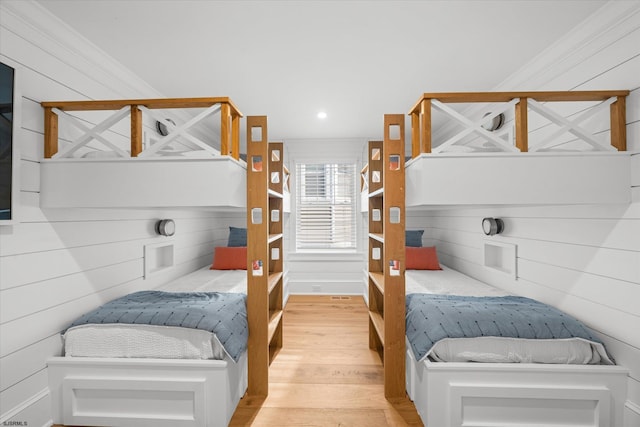 bedroom with wood-type flooring and wooden walls