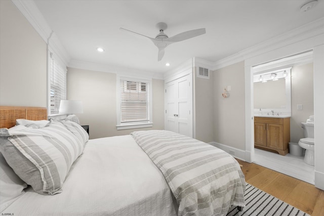 bedroom featuring a closet, crown molding, ceiling fan, light hardwood / wood-style flooring, and ensuite bathroom