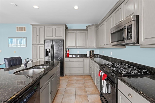 kitchen featuring dark stone counters, gray cabinets, sink, black appliances, and light tile patterned floors