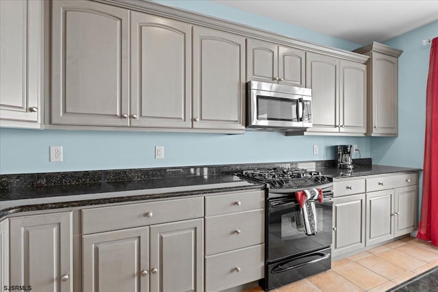 kitchen with dark stone countertops, black gas stove, and light tile patterned floors