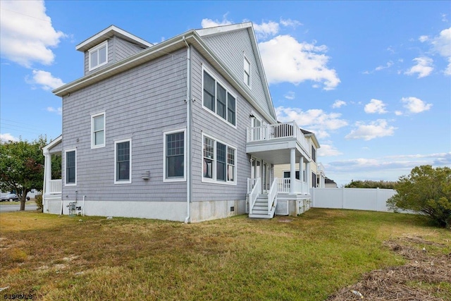 back of house with a lawn and a balcony