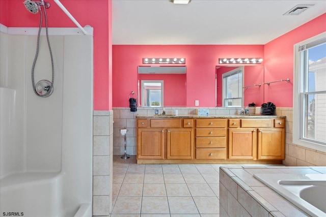 bathroom featuring vanity, tile walls, a bathing tub, and tile patterned floors