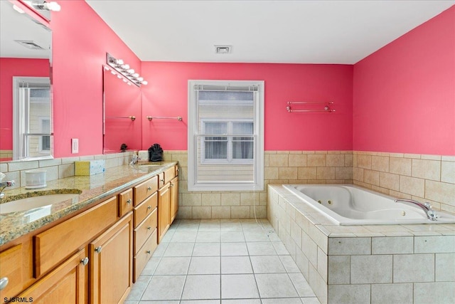 bathroom with tile patterned flooring, tiled bath, and vanity