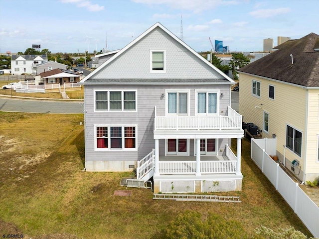 rear view of house with a balcony and a yard