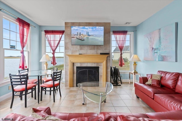 tiled living room featuring a wealth of natural light, a water view, and a tiled fireplace