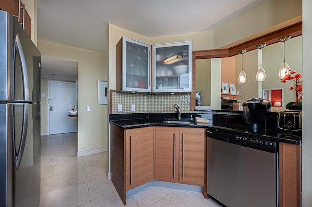 kitchen featuring dark stone counters, sink, backsplash, appliances with stainless steel finishes, and decorative light fixtures