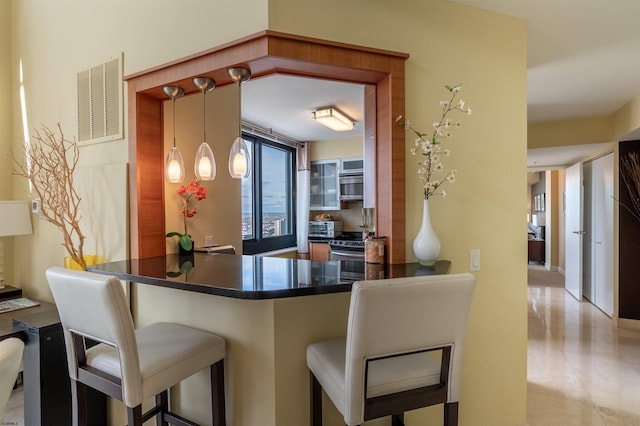 kitchen with appliances with stainless steel finishes, backsplash, kitchen peninsula, and a breakfast bar area