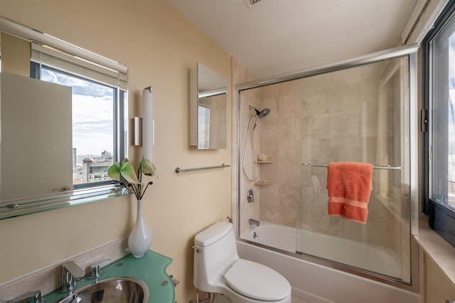 full bathroom with enclosed tub / shower combo, toilet, and sink