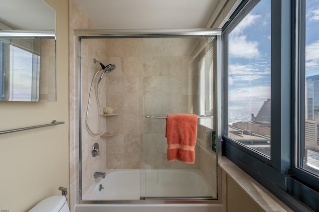 full bathroom with enclosed tub / shower combo, toilet, and a healthy amount of sunlight