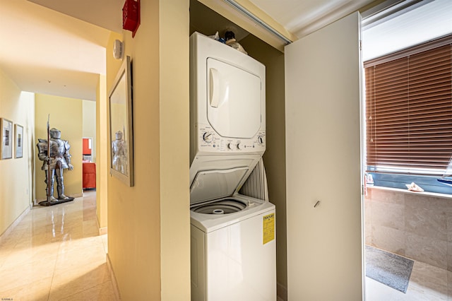 laundry room featuring stacked washer / dryer and light tile patterned flooring