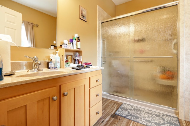 bathroom with a shower with shower door, hardwood / wood-style flooring, and vanity